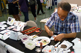 Many people stopped by to view Mr. Aasakura's special technique in painting postcard size art, his technique of shading the colors and featuring delicate and real life pictures.