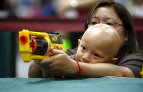 Mom helps with the cork gun. Which toy are they aiming for?